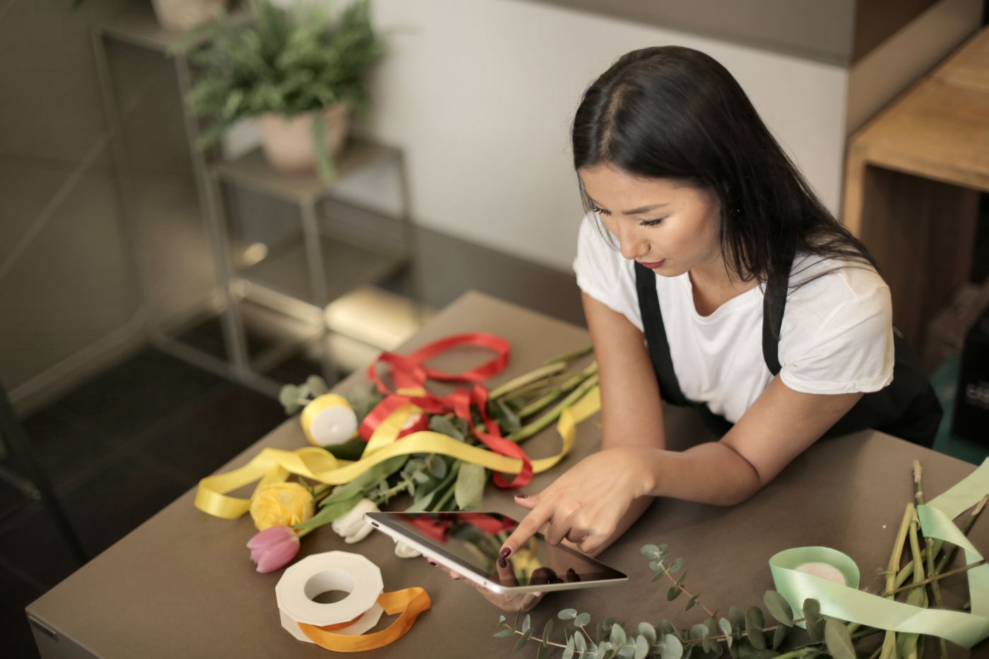 Butiksejer med en tablet blandt blomster og bånd